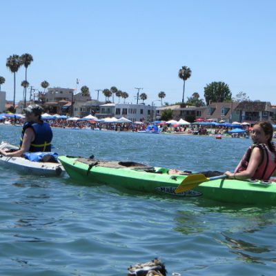 Two people in a kayak with people celebrating